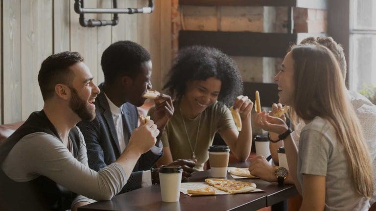 Group of people smiling and eating pizza