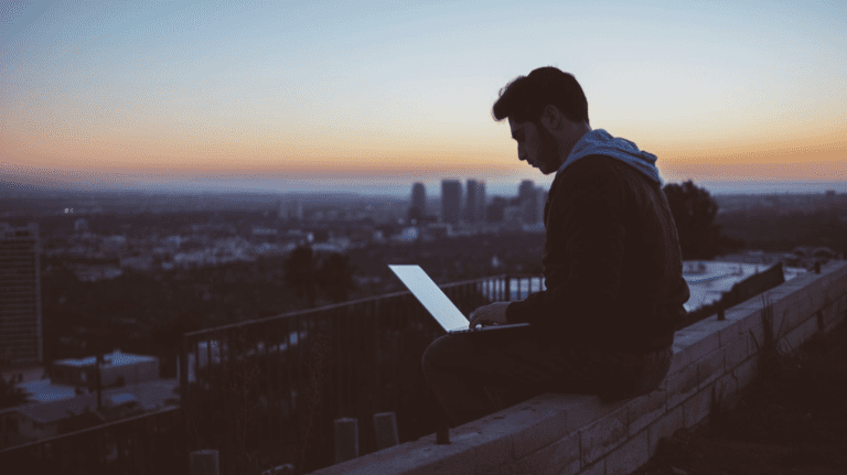 man on laptop watching sunset