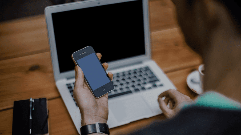 man working on laptop and mobile phone